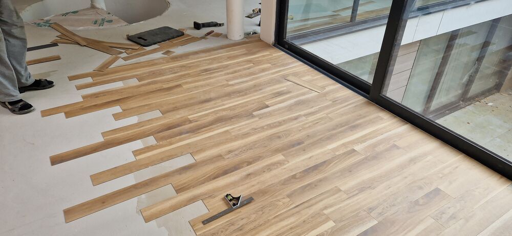 Graham Holmes laying a real wood floor next to patio doors on a job in Essex
